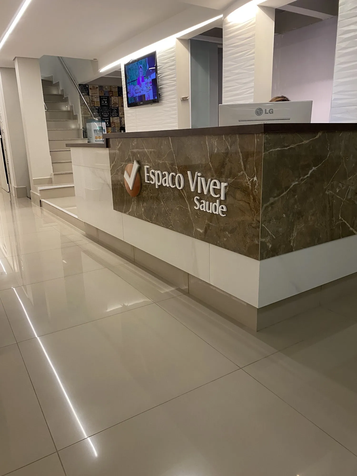 Recepção com balcão de mármore e escada ao fundo